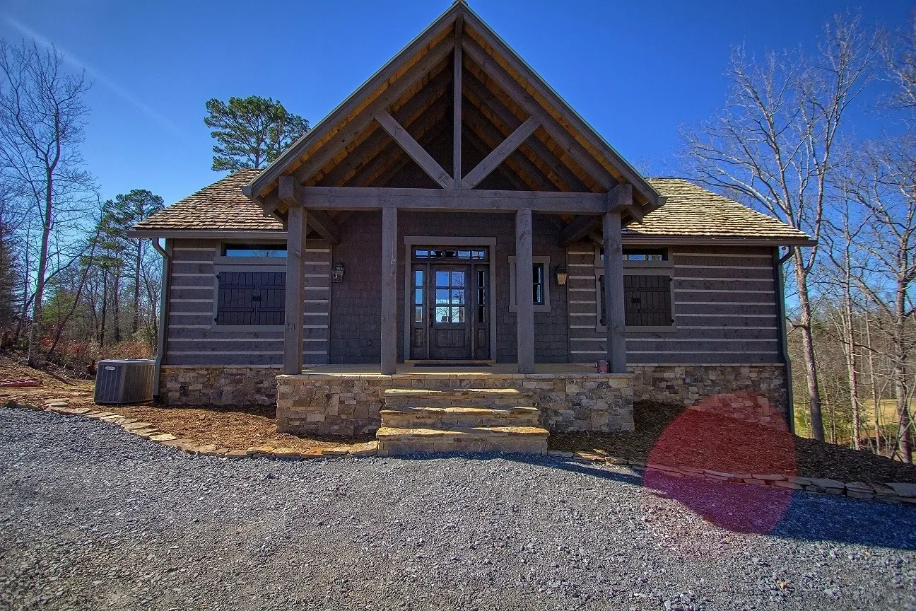 A large log cabin with a porch and stone steps.