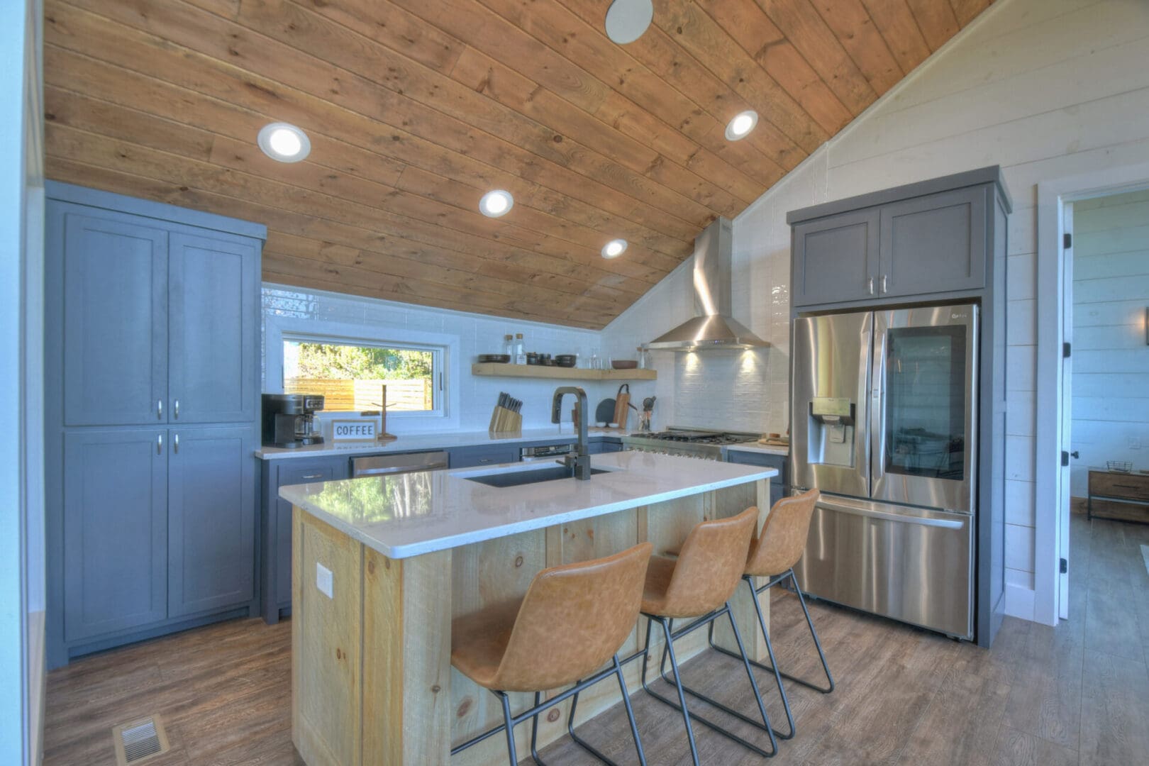 A kitchen in a tiny house with wood ceilings, designed by an architect specializing in architectural design services.