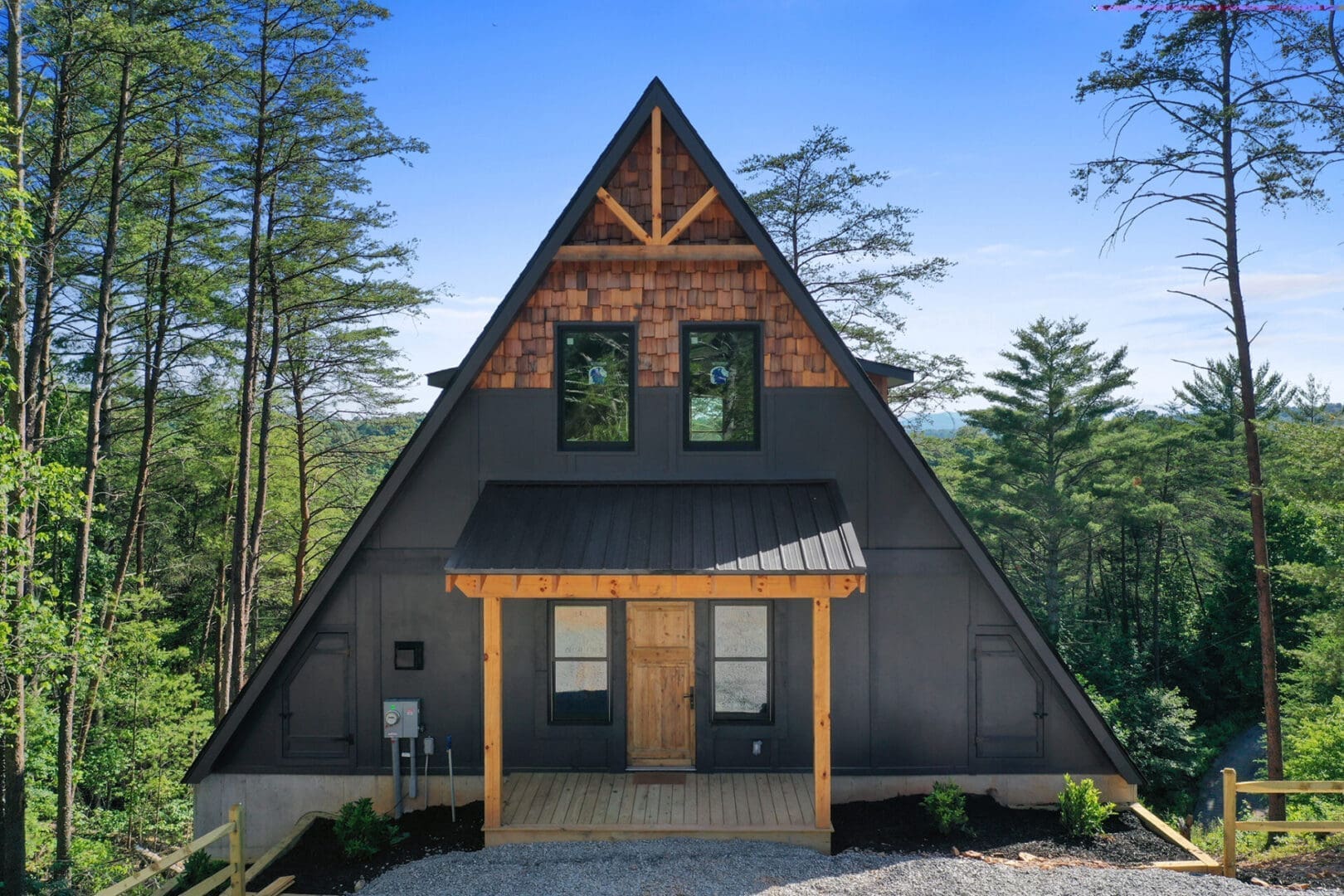 Architectural Design Services: A black a-frame house in the woods.